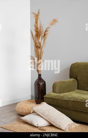 Vase mit Pampasgras auf Rattanpouf im Wohnzimmer Stockfoto