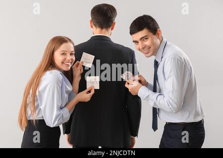 Geschäftsleute, die ihren Kollegen vor hellem Hintergrund einen Streich spielen. Feier zum 1. April Stockfoto