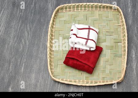 Rot-weiße Stoffservietten gefaltet, um Brot oder Tortillas zu bedecken, die in einem Korb auf einem klassischen grauen Holztisch liegen Stockfoto