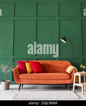 Stilvolles Wohnzimmer mit rotem Sofa, Trittleiter und Lampe Stockfoto