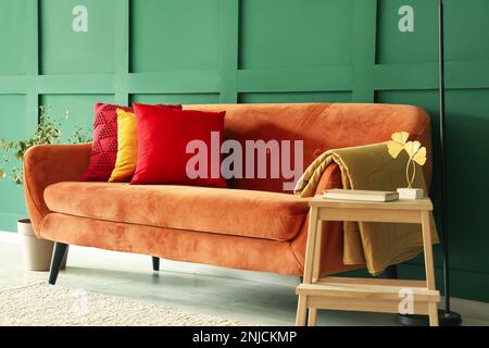 Rotes Sofa mit stilvollen Kissen im Wohnzimmer Stockfoto