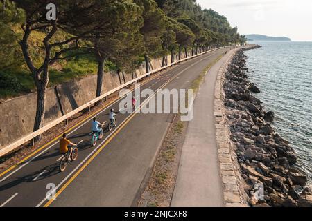 Vater, Mutter und ihre beiden Kinder fahren Fahrrad, genießen einen schönen Sommertag, Drohnenschuss. Aktives Familienurlaubskonzept. Stockfoto