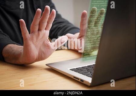 Die Hände werden vom Laptop aus mit Stoppgesten zurückgeworfen, während unbekannter Code auf dem Bildschirm erscheint, das Konzept von Cyberkriminalität wie Hackerangriffen, Ransomware und Stockfoto