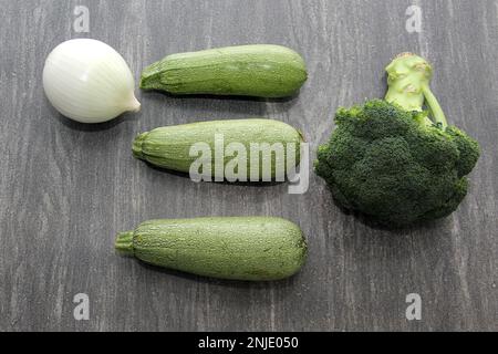 Frisches, rohes und köstliches Gemüse, frisch geerntet und fertig zum Kochen: Brokkoli, Chayote, grüner Kürbis, Zwiebeln auf einem Holztisch Stockfoto