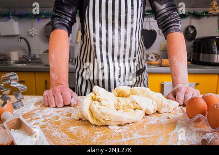 Eine unerfahrene Hausfrau, eine Köchin, weiß nicht, wie man den Teig richtig kneten kann, fragt um Rat. Schlechtes Kochkonzept, Unerfahrenheit Stockfoto