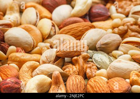 Verschiedene Arten von Nüssen und Samen, Foto mit selektivem Fokus. Geschälte Walnuss, Haselnüsse, geschälte Erdnuss, Pinienkerne, Mandelkerne, Cashewkerne, Stockfoto