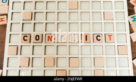 Konfliktwort aus Scrabble-Spielsteinen - Scrabble-Buchstaben auf dem Spielbrett. Hochwertiges Foto Stockfoto