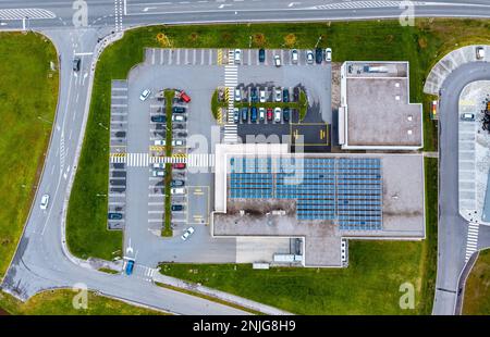 Draufsicht eines Geschäftsgebäudes mit Sonnenkollektoren auf dem Dach. Parkplatz mit bunten Autos. Stockfoto