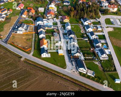 Neue Nachbarschaft mit neuen Häusern. Europäisches Architekturdesign. Viele Wiesen um die Häuser herum. Standort: Braslovce, Slowenien. Stockfoto