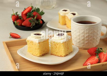 Vanilleschwammelkuchen mit Erdbeermarmelade, serviert mit Tee Stockfoto