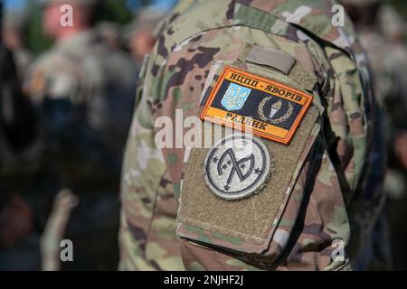 EIN US-AMERIKANISCHER Soldat der Armee, der Task Force Orion, 27. Infanterie-Brigade-Kampfteam, New York Army National Guard, zugewiesen wurde, trägt das Combat Training Center-Yavoriv Advisor Patch über dem 27. IBCT Patch während der Joint Multinational Training Group-Ukraine Transfer of Authority Zeremonie in Grafenwoehr, Deutschland, 8. August 2022. Die Task Force Orion übernahm die JMTG-U-Mission von Task Force Gator, 53. IBCT, Florida Army National Guard, und wird auch weiterhin die Kampffektivität der Ausbildung ukrainischer Militärs in Systemen und Ausrüstungen gewährleisten, die im Rahmen der US-Präsidentschaftswunde ausgestellt wurden Stockfoto