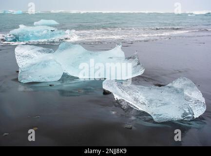 Diamond Beach in Island. Unglaubliche Landschaft mit reinen blauen Eisbergen auf schwarzem Sand. Ufer in der Nähe der Jokulsarlon-Gletscherlagune. Das Konzept Der Globalen Erwärmung Stockfoto