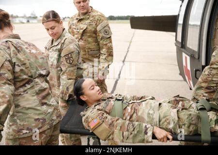 USA Soldaten der 1171. Medical Company, Michigan National Guard, und der 477. Medical Company, USA Army Reserves, Duluth, Minnesota, nehmen Sie SPC. Melissa Bellgreen 1171. Medical Company, Michigan National Guard vom Hubschrauber während des Trainings mit heißen und kalten Lasten, am Grayling Army Airfield, Grayling, Michigan, während der Übung Northern Strike 22-2. August 8, 2022. Northern Strike wurde entwickelt, um über 7.400 Servicemitarbeiter mit verschiedenen Schulungsformen herauszufordern, die die Interoperabilität zwischen mehreren Komponenten, multinationalen und behördenübergreifenden Partnern fördern. Stockfoto