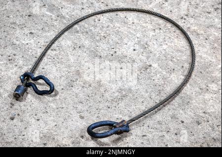 Drahtseilschlinge mit Ösen an den Enden auf Betonoberfläche Stockfoto