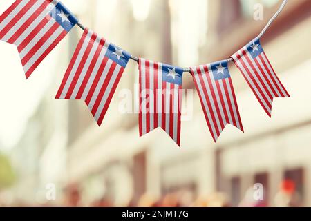 Eine Girlande mit liberianischen Nationalflaggen auf abstraktem, verschwommenem Hintergrund. Stockfoto