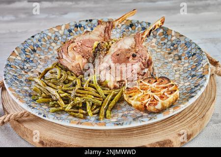 Lammriegel, mittelgroß, gebacken mit grünen Bohnen und Knoblauch. Stockfoto