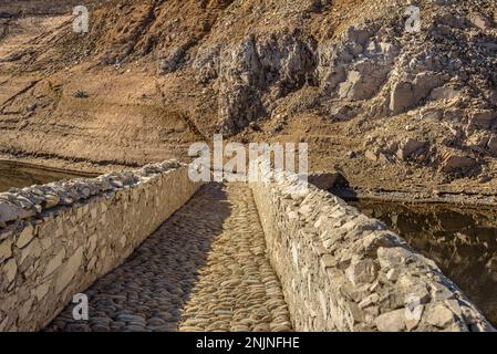 Die mittelalterliche Brücke Querós im Susqueda-Reservoir, die nach dem Bau des Reservoirs unter Wasser stand und in Zeiten starker Dürre zu sehen ist Stockfoto