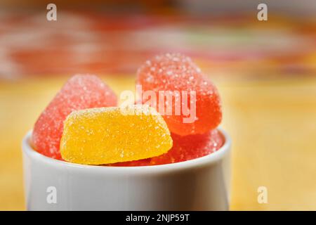 Rote und gelbe Zucker Fruchtbonbons in einer weißen Schüssel, bereit, ungesunde Süßigkeiten zu essen Stockfoto