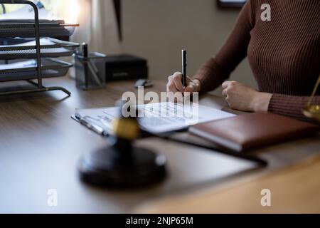 Nahaufnahme des Geschäfts weibliche Hände halten Stift, unterschreiben in weissem Papierformular oder Antrag, um die Vertragsvereinbarung zu bestätigen und auf dem Tisch abzutreten Stockfoto