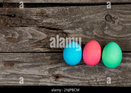 Osteressen, bunte Hühnereier auf einem alten Holztisch am Abend Stockfoto