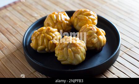 Penellets. Kleine Süßigkeiten verschiedener Formen, aus Mandel- und Kartoffelteig hergestellt und mit Mandeln oder Pinienkernen bedeckt. Stockfoto