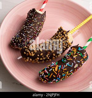 Bananen in dunkle Schokolade getaucht und mit dekorativem Karamell bedeckt. Stockfoto