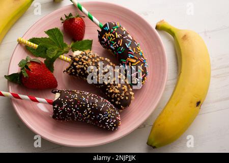 Bananen in dunkle Schokolade getaucht und mit dekorativem Karamell bedeckt. Stockfoto