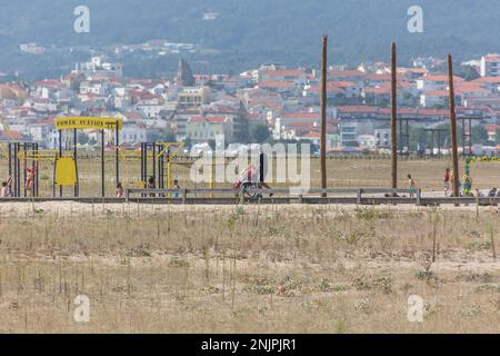 Figueira da Foz Portugal 08 09 2022: Blick auf einen Mann, der mit einer Frau auf hölzernen Fußgängerwegen von Figueira da Foz, Claridade Beach, im Rollstuhl sitzt Stockfoto