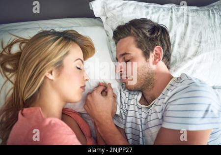 Wie Seelenverwandte schlafen. Ein friedliches junges Paar, das im Bett von Angesicht zu Angesicht miteinander schläft. Stockfoto