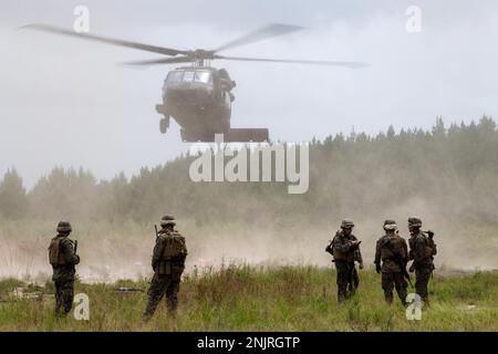 Marines, die der Marine Wing Support Squadron 273 zugeteilt wurden, Marine Air Control Group 28, MCAS Beaufort, South Carolina, warten auf einen UH-60 Blackhawk, um mit Soldaten zu landen, die dem 4. Bataillon, 3. Luftfahrtregiment, 3. Kampfluftbrigade, 3. Infanteriedivision in Fort Stewart, Georgia, 10. August 2022. Marines und Soldaten führten eine gemeinsame vordere Bewaffnungs- und Tankstelle durch, um die Fähigkeit zur Einrichtung und Aufrechterhaltung von FARP-Operationen zu verbessern. Stockfoto