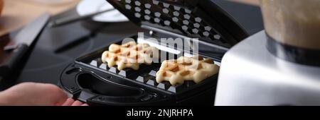 Frau bereitet hausgemachte belgische Waffeln in der Küche zu Stockfoto
