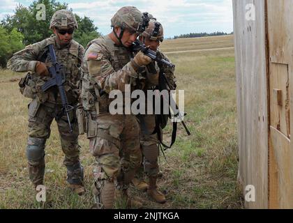 Staff Sgt. Ryne Reyes, Leiter des 21. Teams des "Theater Sustainment Command", bereitet sich darauf vor, die Tür eines Zielgebäudes zu durchbrechen, als SPC. Jadin Anderson, SPC. Nicholas Diercks und PFC. Gabriel Carrington bietet unterstützende Deckung während der USA Army Europe and Africa Best Squad Competition, Grafenwohr, Deutschland, 10. August 2022. Teams aus allen USAREUR-AF testen ihre taktische Kompetenz, Kommunikation und allgemeinen Zusammenhalt, während sie um den Titel „Best Squad“ kämpfen. Die Gewinner dieses Wettbewerbs werden USAREUR-AF in den USA vertreten Army Best Squad Competition in Fort Bragg, North C. Stockfoto
