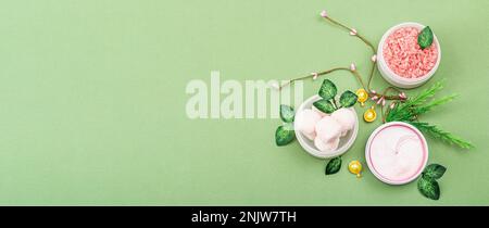 Wellness- und Spa-Zusammensetzung mit rosafarbenen natürlichen Zutaten. Kosmetische Schönheits-Hautpflege im Hintergrund. Trendiges Savannahgrün, flach liegend, Banner Stockfoto