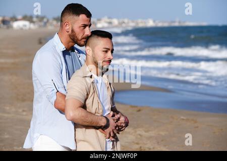 Ein Mann, der seinen Freund umarmt, während er zusammen am Strand steht. Stockfoto