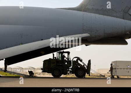 Ein Geländewagen 10K schleppt eine Reaper-Drohne der General Atomics MQ-9 in Richtung einer Lockheed C-5M Super Galaxy, die der 22. Luftwaffenstaffel am 10. August 2022 auf dem Luftwaffenstützpunkt Al Dhafra, Vereinigte Arabische Emirate, zugeteilt wurde. Die Reaper können zur schnellen Wiederverwendung in Lagerbehälter, sogenannte „Särge“, zerlegt werden. Stockfoto