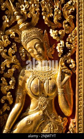 Laos: Eine Eingangstür dekoriert mit einer Szene aus dem hinduistischen, epischen Ramayana (in Laos bekannt als Phra Lak Phra Lam), dem königlichen Begräbnis Carriage House, Wat Xieng Thong (Goldener Stadttempel), Luang Prabang. Wat Xieng Thong mit seinen flachen, weitläufigen Dächern verkörpert den klassischen Luang Prabang-Stil, wurde 1560 von König Setthathirat (1548–71) erbaut und bis 1975 von der Monarchie bevormundet. Luang Prabang war früher die Hauptstadt eines Königreichs mit demselben Namen. Bis zur kommunistischen Machtübernahme im Jahr 1975 war es die königliche Hauptstadt und der Sitz der Regierung des Königreichs Laos. Die Stadt ist heute eine UNES Stockfoto