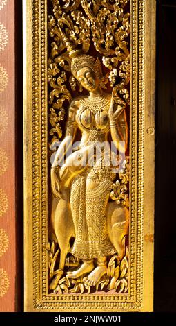 Laos: Eine Eingangstür dekoriert mit einer Szene aus dem hinduistischen, epischen Ramayana (in Laos bekannt als Phra Lak Phra Lam), dem königlichen Begräbnis Carriage House, Wat Xieng Thong (Goldener Stadttempel), Luang Prabang. Wat Xieng Thong mit seinen flachen, weitläufigen Dächern verkörpert den klassischen Luang Prabang-Stil, wurde 1560 von König Setthathirat (1548–71) erbaut und bis 1975 von der Monarchie bevormundet. Luang Prabang war früher die Hauptstadt eines Königreichs mit demselben Namen. Bis zur kommunistischen Machtübernahme im Jahr 1975 war es die königliche Hauptstadt und der Sitz der Regierung des Königreichs Laos. Die Stadt ist heute eine UNES Stockfoto