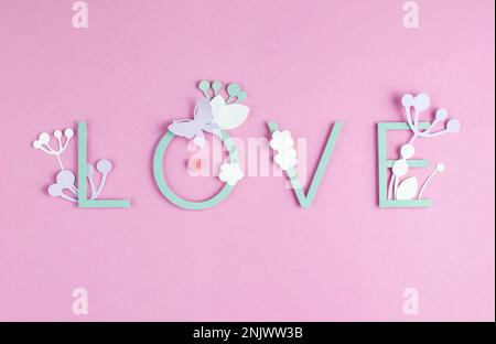 Romantische Komposition in Pastelltönen mit Schriftzug „Love“, Illustration aus Papier auf pinkfarbenem Hintergrund. Stockfoto