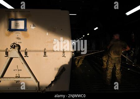 Ein Flugzeugführer der 380. Expeditionary Logistics Readiness Squadron und der 60. Aircraft Maintenance Squadron arbeiten zusammen, um eine General Atomics MQ-9 Reaper Drohne an Bord einer Lockheed C-5M Super Galaxy zu bringen, die der 22. Airlift Squadron am 10. August 2022 auf dem Luftwaffenstützpunkt Al Dhafra, Vereinigte Arabische Emirate, zugewiesen wurde. Nachdem der 380. Air Expeditionary Wing seit Juni neun neue MQ-9s erhalten hatte, wurden fünf wieder in die USA verlegt. Stockfoto