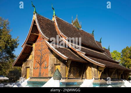 Wat Xieng Thong mit seinen flachen, weitläufigen Dächern verkörpert den klassischen Luang Prabang-Stil, wurde 1560 von König Setthathirat (1548–71) erbaut und bis 1975 von der Monarchie bevormundet. Luang Prabang war früher die Hauptstadt eines Königreichs mit demselben Namen. Bis zur kommunistischen Machtübernahme im Jahr 1975 war es die königliche Hauptstadt und der Sitz der Regierung des Königreichs Laos. Die Stadt gehört heute zum UNESCO-Weltkulturerbe. Stockfoto