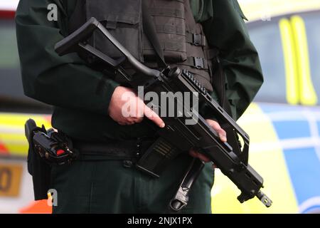 Ein bewaffneter Polizist im Dienst nahe des Sportkomplexes in der Gegend der Killyclogher Road von Omagh, Co Tyrone, wo außerdienstlicher PSNI Detective Chief Inspector John Caldwell mehrmals von maskierten Männern vor jungen Leuten erschossen wurde, die er trainiert hatte. Herr Caldwell befindet sich nach dem Angriff am Mittwochabend im Krankenhaus in einem kritischen, aber stabilen Zustand. Foto: Donnerstag, 23. Februar 2023. Stockfoto