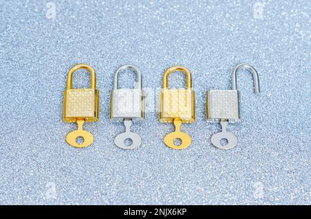 Reihe mit vier glänzenden Metallvorhängeschlössern mit Generalschlüsseln auf glitzerndem Hintergrund. Kreatives Datenschutzkonzept. Stockfoto