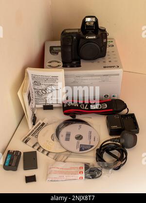 Eine Canon 5D DSLR-Kamera mit dem dazugehörigen Handbuch, Akku, Ladegerät, Kabeln und irreführendem Schultergurt für einen Canon 7d MK II Stockfoto