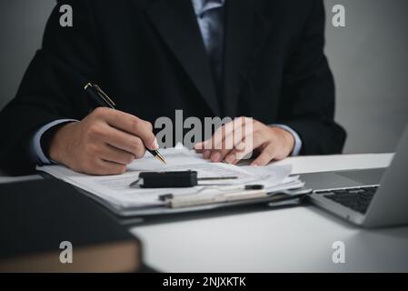 Autohändler-Geschäftsmann unterschreibt Autoversicherung. Autokauf- und Versicherungskonzept. Stockfoto