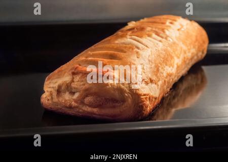 Ein gebackenes hausgemachtes Brötchen mit Apfelmarmelade im Elektroofen: Nahaufnahme Stockfoto