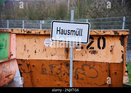 Orangene Müllcontainer mit Beschriftung für die Müllart die abgegeben werden darf. Hausmüll. Stockfoto