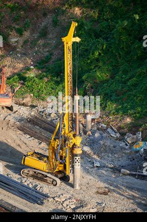 Der gelbe Pfahltreiber steuert die Fundamentpfähle auf der Baustelle. Stockfoto