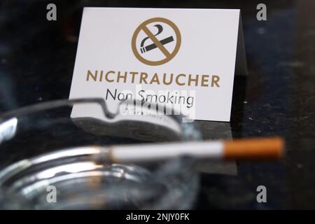 Zigarette im Aschenbecher und Rauchverbot-Schild Stockfoto