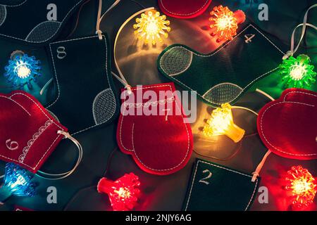 Filzstrümpfe, Fäustlinge und Feenlichter als schöne Weihnachtsdekoration. Adventskalender für Kinder. Ich warte auf den Feiertag Stockfoto