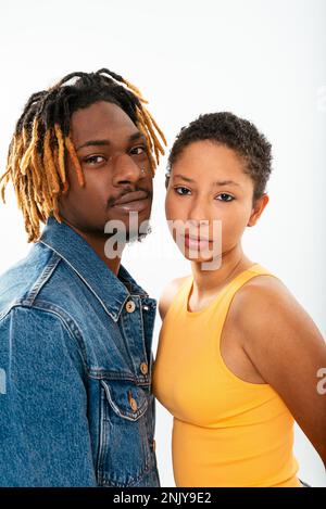 Seitenansicht eines afroamerikanischen Freundes mit Dreadlocks in Jeansjacke mit Freundin mit kurzen Haaren im Studio Stockfoto